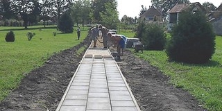 Sárháton járdalapokból építik a parkon átvezető utat